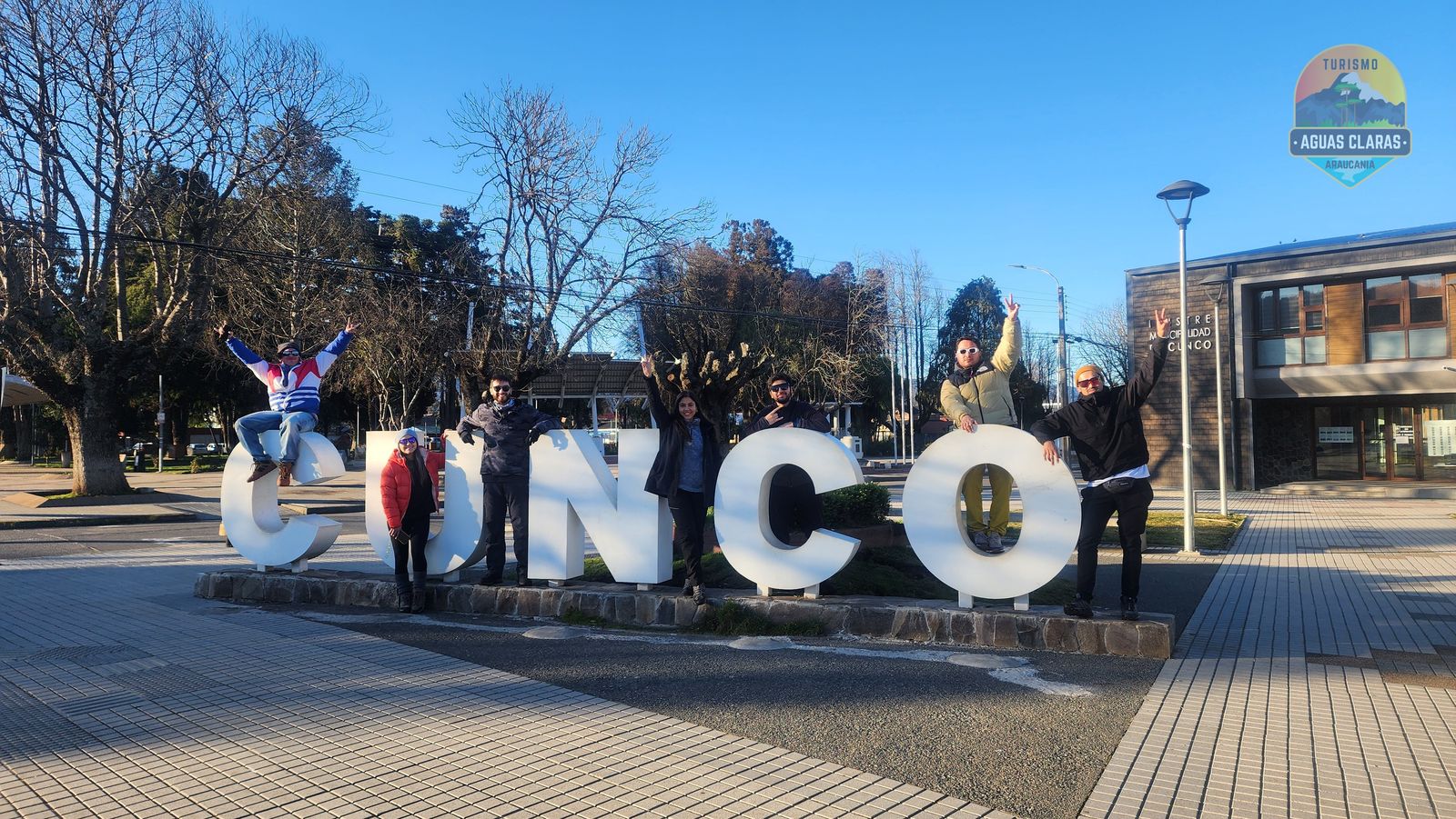 Grupo de pasajeros celebrando junto a las letras de Cunco